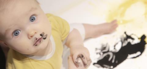 Vauva maalaa mustalla värillä taideteosta.