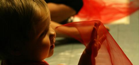 Vauva heiluttaa punaista sirkushuivia.