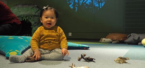 Taapero istumassa Rullan elämystilan lattialla. Edessä muovisia lelueläimiä.