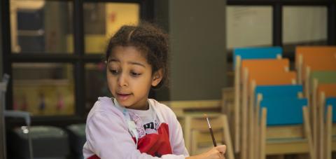 Lapsi maalaa vesivärisiveltimellä.