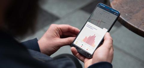 Hands holding a mobile phone with a screen showing a view of the Tampere Pulse tool.