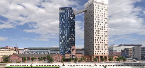 Kuvassa aseman miljootä, junia ja kaksi tornimaista taloa.