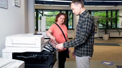 Two people at the printer.