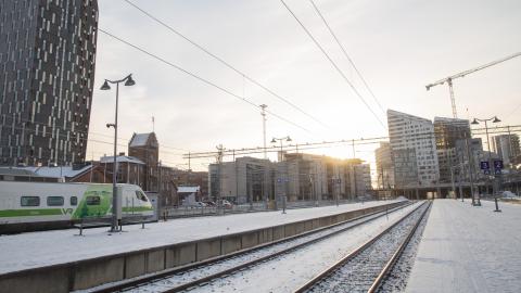 Aamuaurinkoinen kuva rautatieasemasta radoilta kuvattuna.