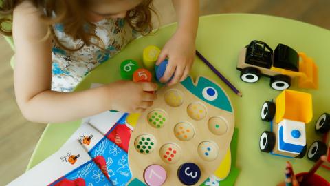 Lapsi tekee pöydän ääressä kalan muotoista numeropalapeliä.