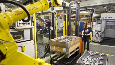 Mies siirtää pumppukärryllä osia tuotantolaitoksessa