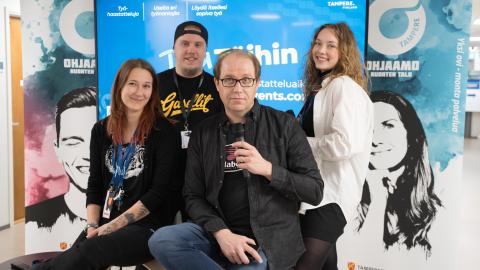 Neljä henkilöä poseeraamassa television edessä. 