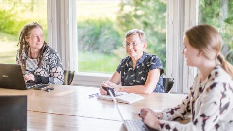 Kolme naista työpöydän äärellä suunnittelemassa.