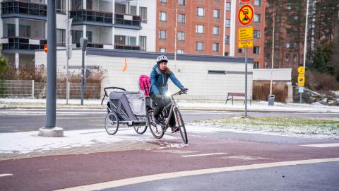 Talvipyöräilijä peräkärröyneen kääntyy pyörätielle.