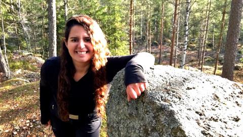 Catherine Ghersi nojaa isoon kiveen metsän keskellä 