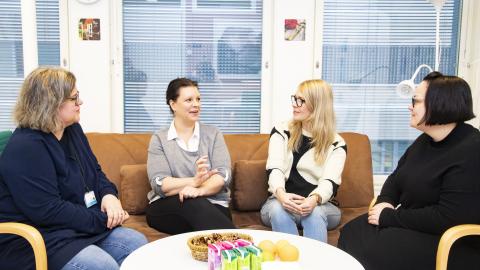 Neljä kriisityöntekijää istuu nojatuoleissa juttelemassa.