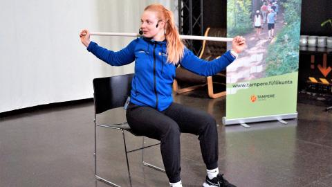 Liikunnanohjaaja ohjaa tuolijumppaa.