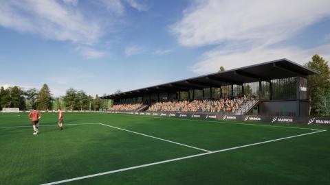 Jalkapallokentällä kaksi pelaajaa ja taustalla kasomossa näkyy katsojia istumassa katoksen alla.