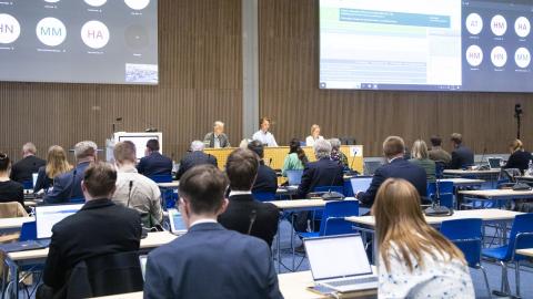 kaupunginvaltuusto kokouksessaan, ihmisiä istumassa pöytiensä ääressä ja puheenjohtaja edessä johtamassa puhetta isossa Tampere-talon salissa.