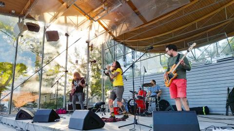 Laulaja ja soittajat lavalla puistokonsertissa.