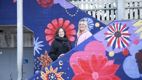Mia Carita Hahl and Elina Laukkala, teachers of the preparatory class of Hatanpää School’s Koivistontie building, stand in the concrete staircase, which has been painted in floral colours.