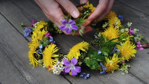 Luonnonkukista tehty kukkaseppele lankkulattialla.
