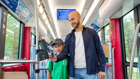 Mies ja poika leimaavat liput ratikassa