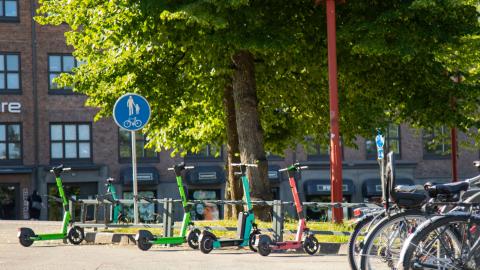 Pysäköityjä sähköpotkulautoja polkupyörätelineissä.