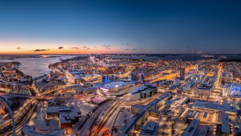 Captured during the serene blue hour, this drone image showcases the Nokia Arena and the surrounding cityscape, bathed in the glow of hundreds of twinkling lights that illuminate the roads and residences.