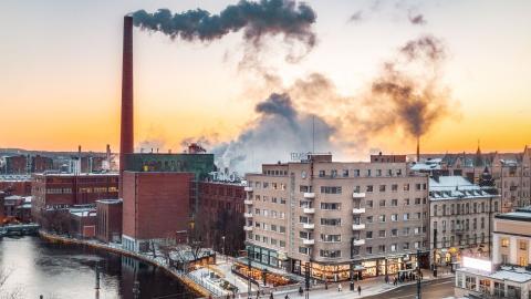 Raitiovaunu talvisella Hämeensillalla, taustalla savua piipuista kellertävälle taivaalle.