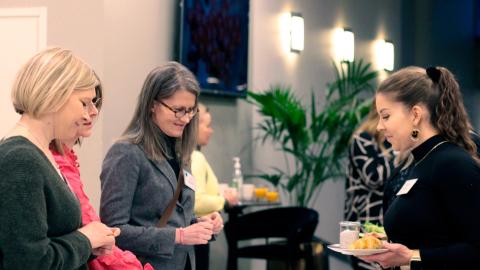 Neljä henkilöä tutkii pöydällä olevia työpajan materiaaleja kokoustilassa.