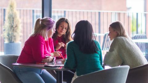 Neljä naista ideoimassa pöydän ääressä.