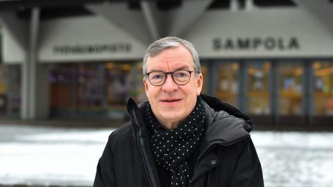 Henkilö seisoo Sampola-rakennuksen edessä.