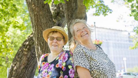 Kaksi iloista naista selät vastakkais kesällä puistossa.