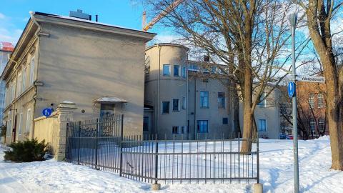 Vaaleapintainen Frenckellin konttori talvisessa maisemassa, aidatulla pihalla vanhoja isoja puita.