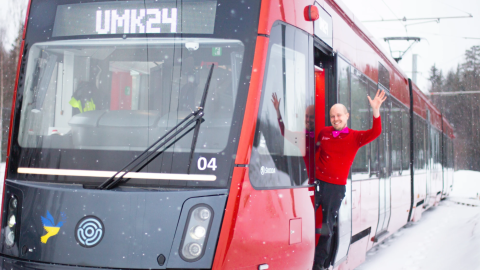 Tram driver waves at the tram door.
