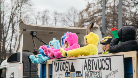Lukion päättävät abiturientit heiluttavat värikkäissä asuissaan penkkari-kuorma-auton lavalta.