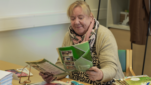 Henkilö tutkii pöydällä olevia vanhoja opinto-oppaita.