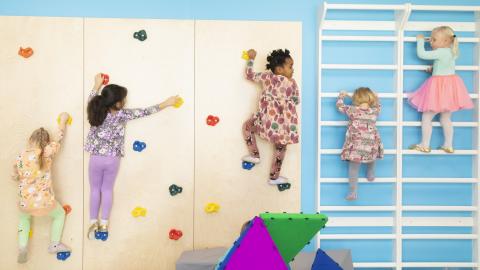 Children bouldering and climbing on the wall.