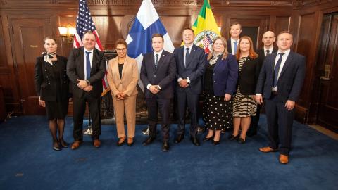 Delegaation väkeä seisoo rivissä kameralle hymyillen. 