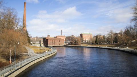 Tammerkoski keväisessä maisemassa. Etualalla vettä ja taustalla rakennuksia.