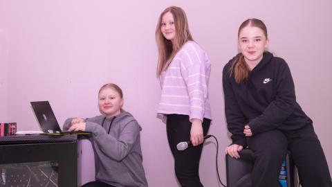 Three children, the one on the left with a lap top.