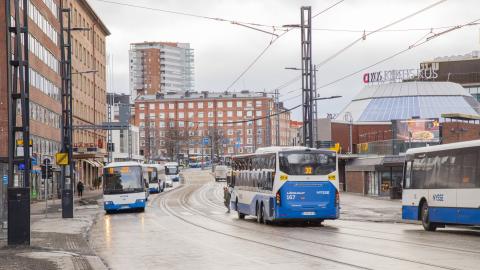 Useita busseja liikenteessä kadulla.