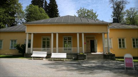 A yellow building with an open porch with four double pillars.