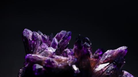 Violetti kivi, jossa useita isoja kiteitä mustalla taustalla. 