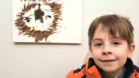 Lapsi ja hänen vasemmalla puolella seinässä kiinni oleva taideteos.