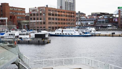 Laukontorin satamassa muutamia veneitä ankkurissa ja taustalla näkyy punatiilisiä rakennuksia sekä taustalla korkea rakennus.