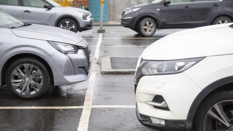 Henkilöautoja parkkiruuduissaan parkkipaikalla, autoista näkyy vain etuosat.