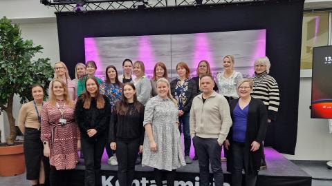 Ihmiset hymyilevät ryhmäkuvassa.