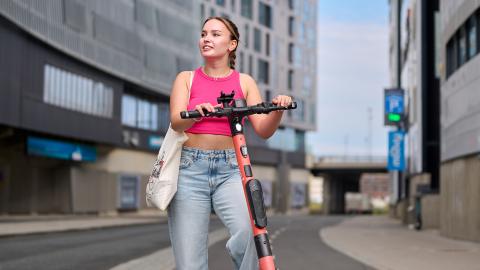 Young woman with an electric scooter looking at the surroundings