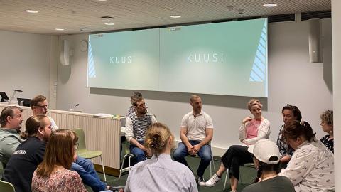 Henkilöt istuvat reingissä ja keskustelevat.