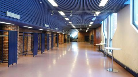 Käytävä, jolla naulakoita ja muutama pystypöytä.