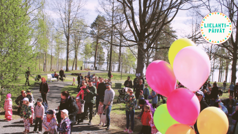 Runsaslukuinen ihmisjoukko viettää aikaa ulkona puistossa.
