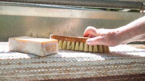 Mäntysaippua, pesuharja ja matto matonpesupaikalla. 