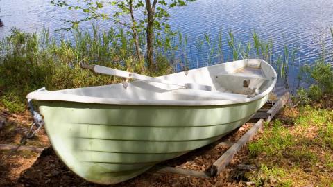 Vaaleanvihreä soutuvene rannalla.